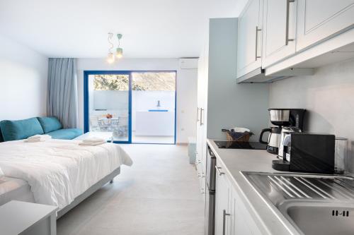 a white kitchen with a bed and a sink at Molos Apartments in Loutro