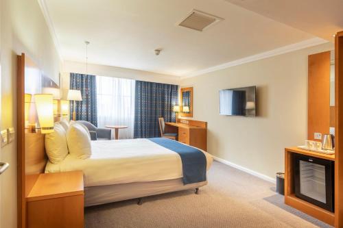 a hotel room with a bed and a television at Holiday Inn London Sutton by IHG in Sutton