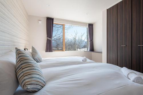 俱知安的住宿－Akiyama，一间卧室设有三张白色的床和窗户