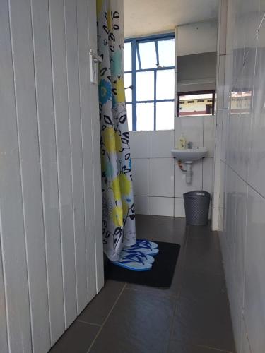 a bathroom with a shower curtain and a sink at Almah Apartments in Kisumu