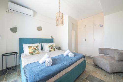 a bedroom with a bed with a blue blanket and a chair at Flaias Gi Villa Retreat in Agia Mavra