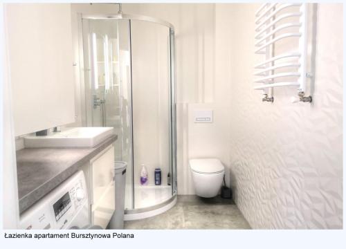a white bathroom with a shower and a toilet at Dom z ogrodem Bursztynowa Polana in Ustka