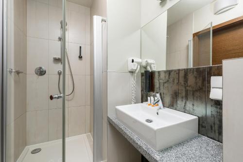 a bathroom with a sink and a shower at Royal Tulip Sand Zdrojowa Mezzanine Hotel Room by Renters in Kołobrzeg