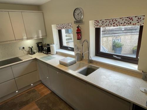 a kitchen with a sink and a clock on the window at The Apartment in Nairn