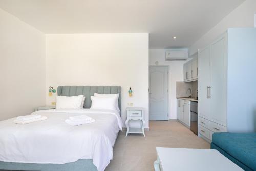 a white bedroom with a large bed and a blue couch at Molos Apartments in Loutro