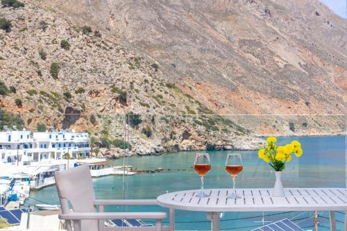 a table with two glasses of wine and flowers on it at Molos Apartments in Loutro