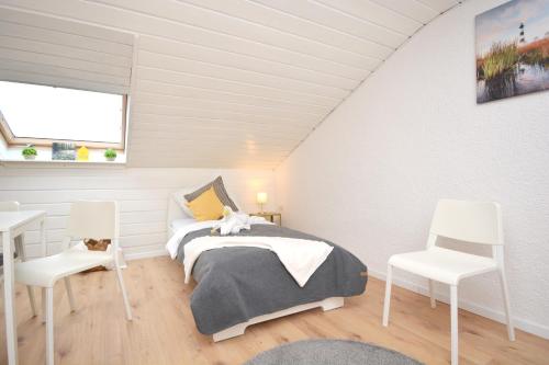 ein Schlafzimmer mit einem Bett und zwei weißen Stühlen in der Unterkunft ERH02-FW Apartment in Herzogenaurach in Herzogenaurach