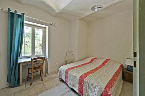 a bedroom with a bed and a desk and a window at Mas Arguin - Charmante maison avec piscine in Barjac
