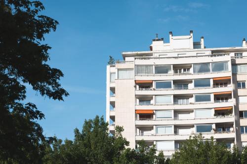 un grand bâtiment blanc avec des arbres devant lui dans l'établissement Le Tresum - Studio near Annecy Lake, à Annecy