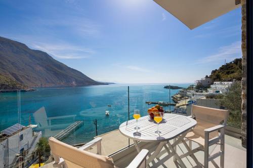 a table and chairs on a balcony with a view of the ocean at Molos Apartments in Loutro