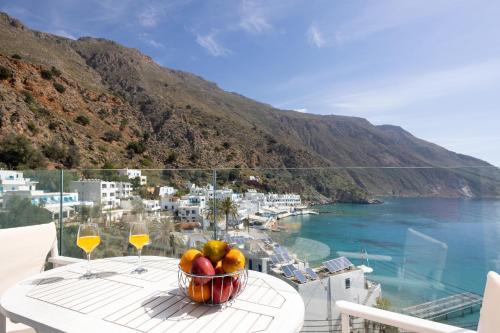 a bowl of fruit on a table with a view of the ocean at Molos Apartments in Loutro
