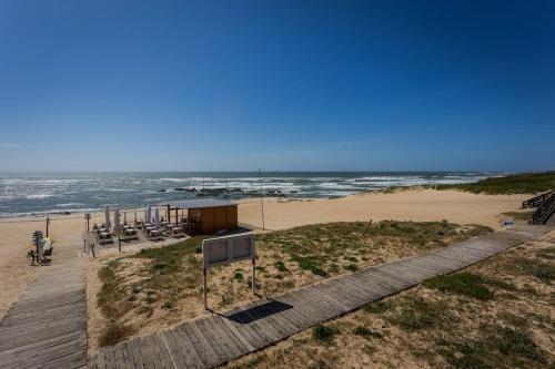 a boardwalk next to a beach with the ocean at 480 Liberdade Apartamento in Labruge