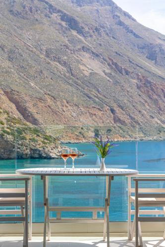 a table with two glasses on it with a view of the water at Molos Apartments in Loutro