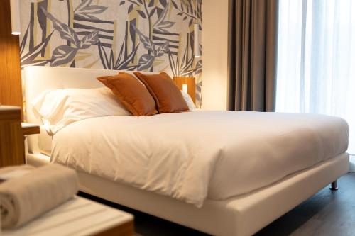 a white bed with two pillows on it in a room at Hotel Aurora in Lido di Jesolo