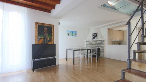 a living room with a dining room table and a television at Italianway - Riva Soldino 9 in Laglio
