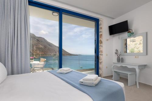 a bedroom with a large window with a view of the ocean at Molos Apartments in Loutro