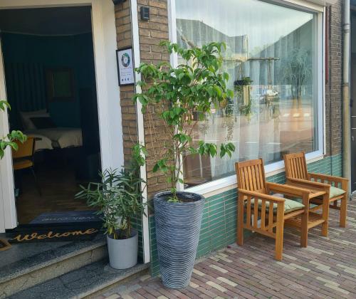 a porch with two chairs and a table and a plant at Feel at Home - Holiday Studio in Gulpen