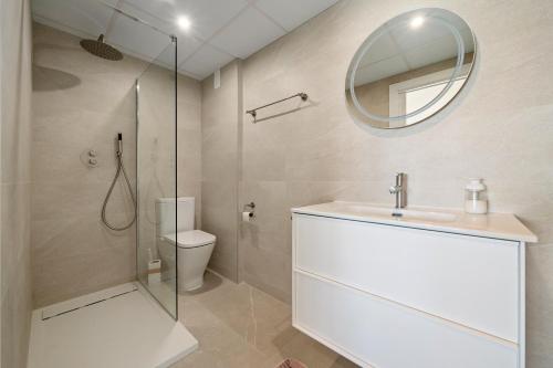 Un baño con inodoro, lavabo y espejo. en Apartamento Pelicano, en Cambrils