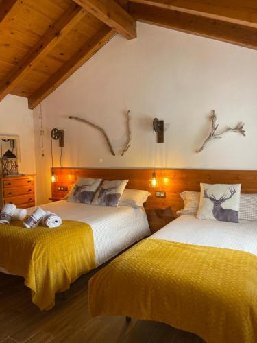 2 Betten in einem Zimmer mit Hirschköpfen an der Wand in der Unterkunft DUPLEX ALPINO in Rialp