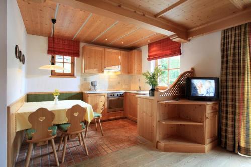 a kitchen with a table with chairs and a television at Appartement Riedl Martin in Brixen im Thale