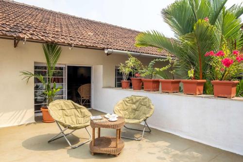 un patio con sillas, mesa y plantas en Nyara Fontainhas Panaji - Heritage villa Goa, en Panaji