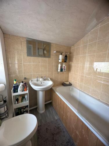 ein Badezimmer mit einem Waschbecken, einer Badewanne und einem WC in der Unterkunft Charming house welcome in Cardiff