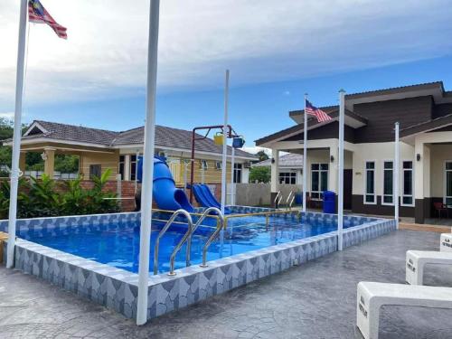 a pool with a slide in front of a house at Aja Retreat Chalet in Jitra