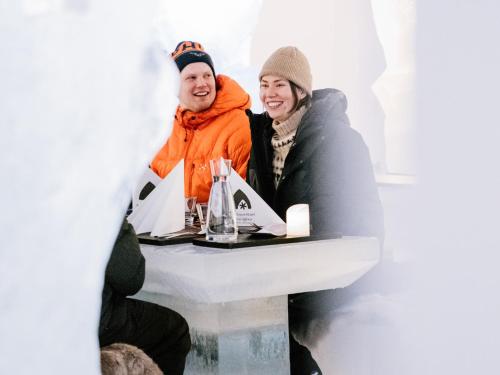 a man and a woman sitting at a table at Arctic SnowHotel & Glass Igloos in Sinettä