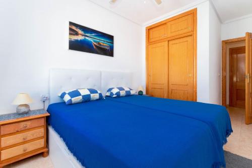 a bedroom with a blue bed and a wooden cabinet at San Sebastián 22 in Torrevieja