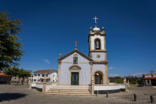 a church with a steeple and a clock tower at 480 Liberdade Apartamento in Labruge