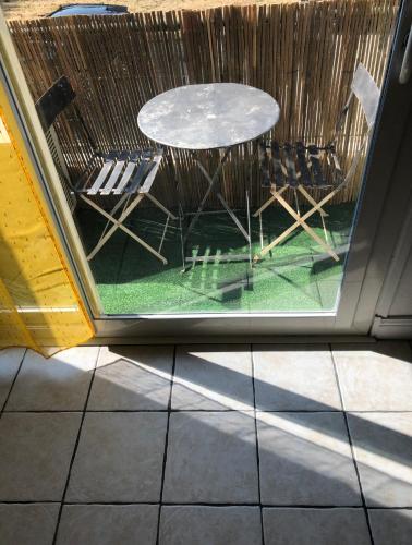 d'une terrasse avec une table et des chaises à travers une fenêtre. dans l'établissement Lo pequelet, à Avignon