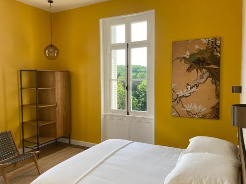 a yellow bedroom with a bed and a window at Villa Paignon in Montbron