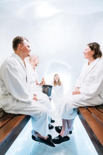 a group of people in white suits sitting on a bench at Arctic SnowHotel & Glass Igloos in Sinettä