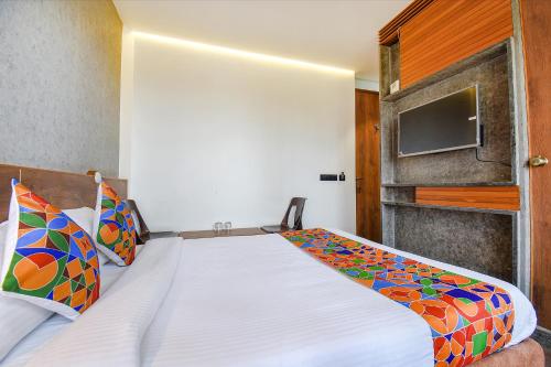 een slaapkamer met een bed en een tv aan de muur bij FabHotel Brown Inn in Pune