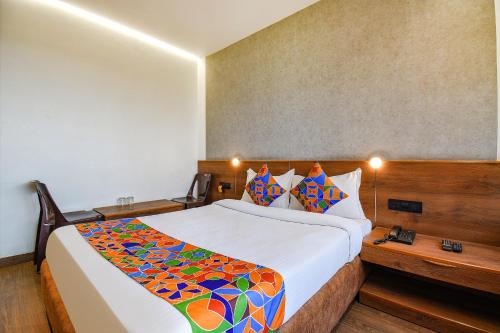 FabHotel Brown Inn في بيون: غرفة نوم مع سرير كبير مع بطانية ملونة