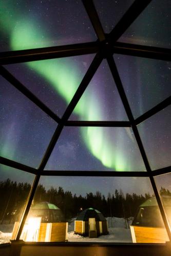 an igloo with a view of the aurora borealis and tents at Arctic SnowHotel & Glass Igloos in Sinettä