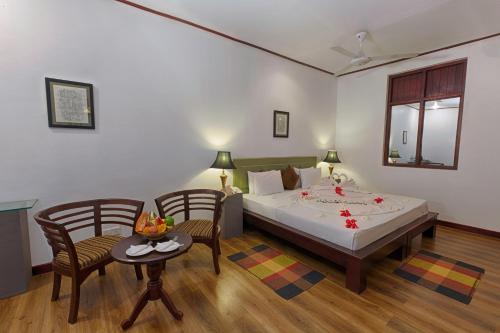 1 dormitorio con 1 cama, 2 sillas y mesa en Kassapa Lions Rock en Sigiriya