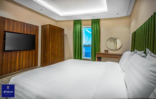 فندق سكناي الياسمين في حائل: غرفة نوم بسرير ابيض كبير وتلفزيون بشاشة مسطحة