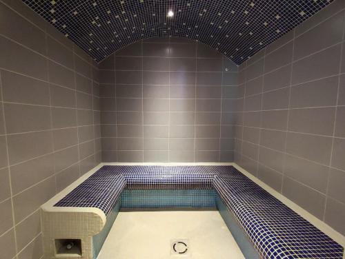 La salle de bains est pourvue d'une douche carrelée de bleu et d'une baignoire. dans l'établissement Résidence Val de Roland, à Luz-Saint-Sauveur