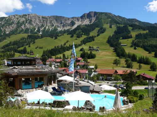 a resort with a pool and mountains in the background at LANIG Hotel Resort&Spa - Wellness und Feinschmeckerhotel - family owned and managed in Oberjoch