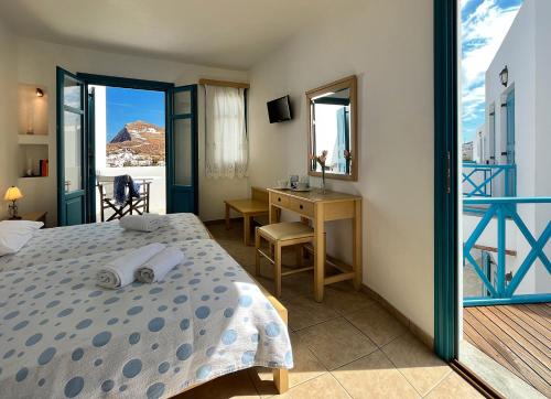 una camera con letto, scrivania e finestra di Horizon Hotel a Chora Folegandros