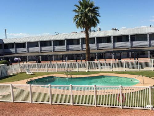 a white fence around a swimming pool with a building at EZ 8 Motel Airporter in Phoenix