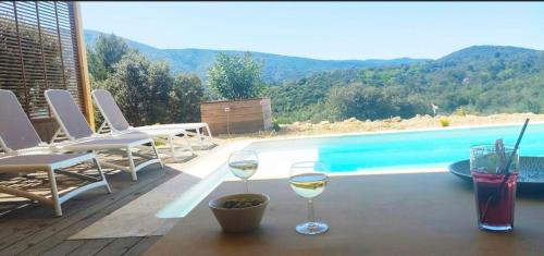 dwa kieliszki wina na stole obok basenu w obiekcie La Bernardière du Ventoux 2 w mieście Mollans-sur-Ouvèze