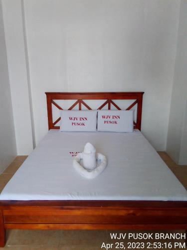 a bed with two pillows and a vase on it at WJV INN PUSOK in Pajo