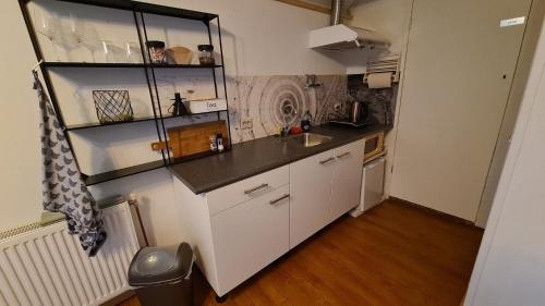 a small kitchen with white cabinets and a black counter top at Rust en Stilte in de Natuur in Onstwedde