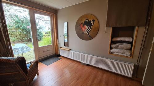 una sala de estar con una ventana y una foto de un gato en la pared en Rust en Stilte in de Natuur, en Onstwedde