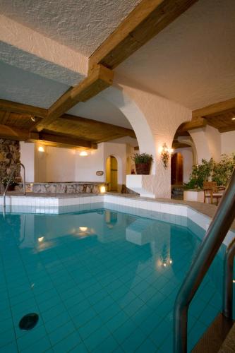 a swimming pool in a hotel with blue water at LANIG Hotel Resort&Spa - Wellness und Feinschmeckerhotel - family owned and managed in Oberjoch