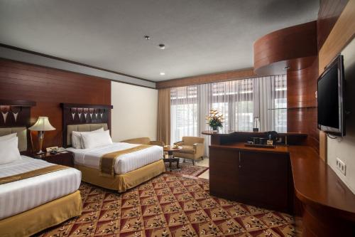 バンドンにあるHotel Savoy Homannのベッド2台、薄型テレビが備わるホテルルームです。
