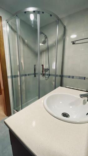 a bathroom with a sink and a glass shower at Alojamiento Fragata Lealtad in Moaña