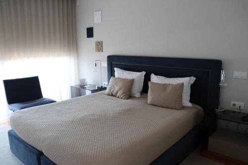 a bed with a blue headboard and a blue chair at FH Hotel Rural in Felgueiras